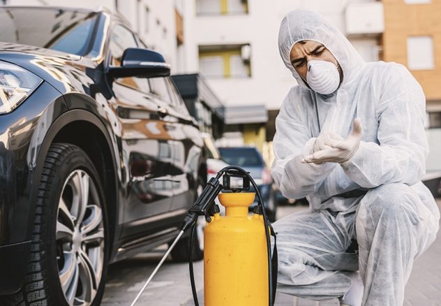 Працівник у спецодязі проводить дезінфекцію автомобіля — санітарна обробка транспорту від бактерій і вірусів. Фахівець проводить дезодорацію салону автомобіля за допомогою спеціального обладнання